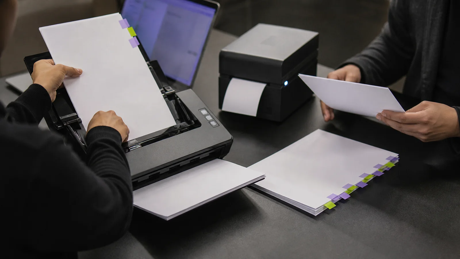 Two people test a document workflow with a scanner, printer and a human exception path.