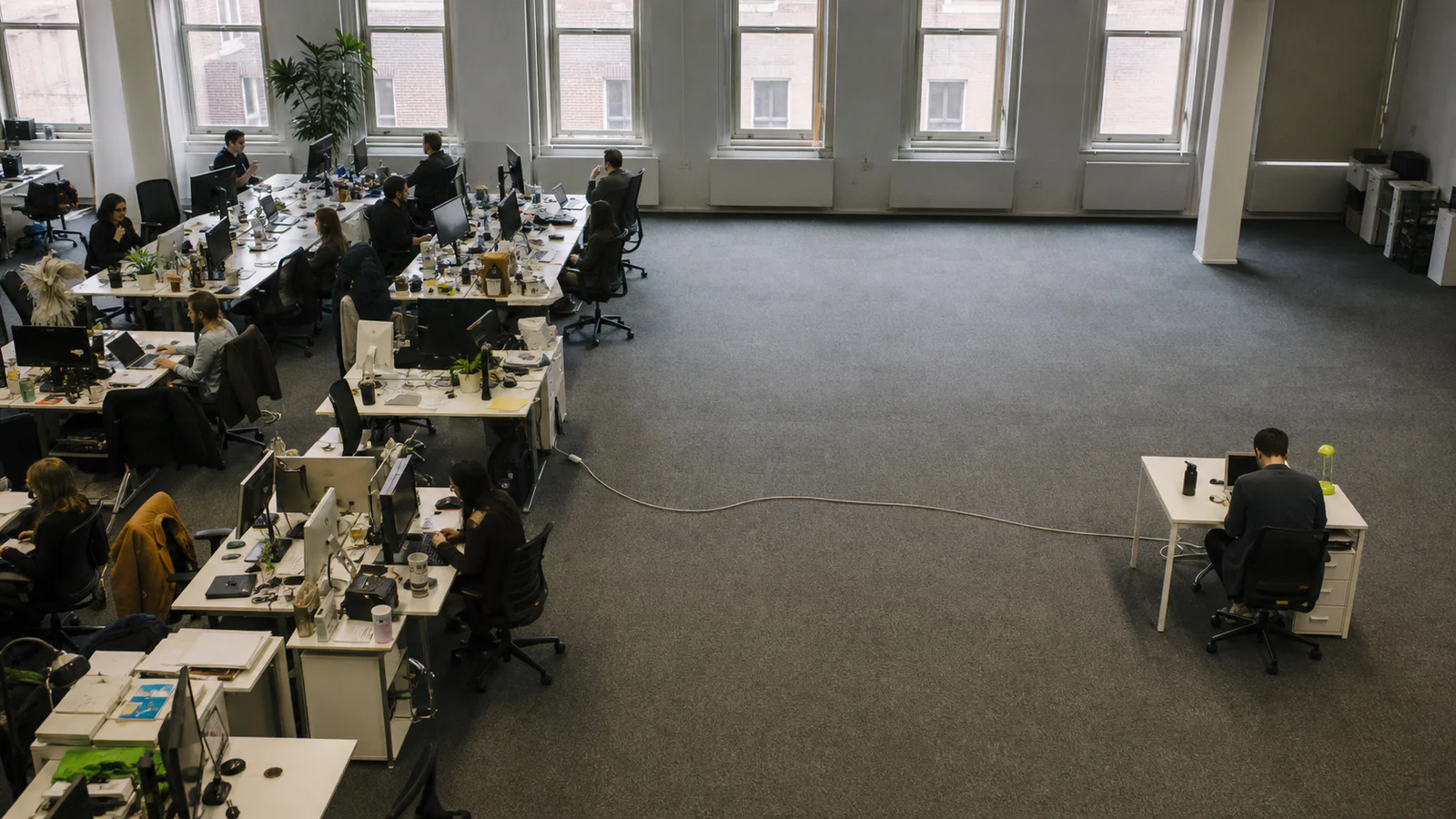 A busy AI operations team separated by empty desks from a lone external user, illustrating the gap between internal and customer adoption.